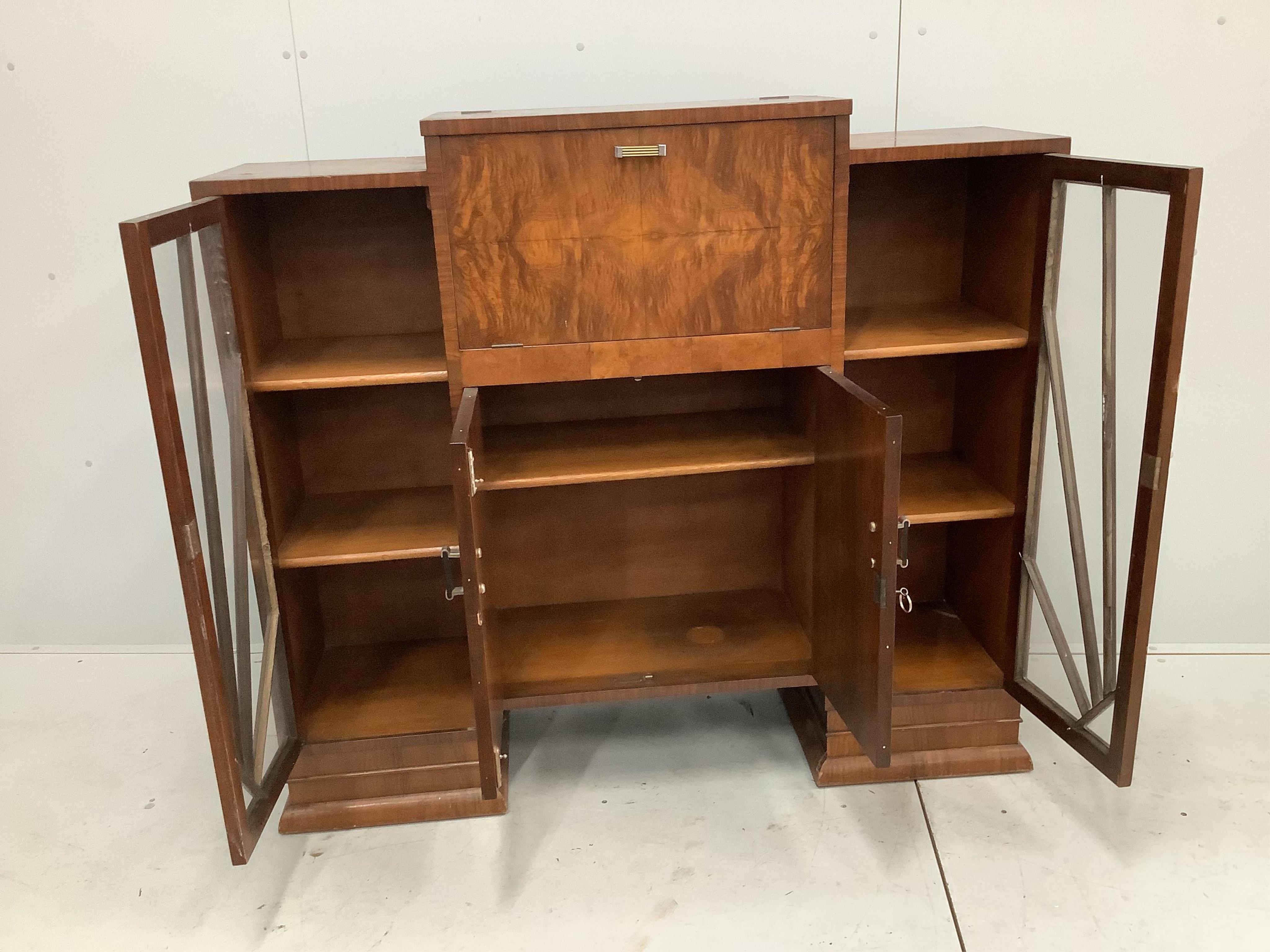 An Art Deco figured walnut cocktail cabinet, width 136cm, depth 39cm, height 123cm. Condition - one glass panel missing, otherwise fair